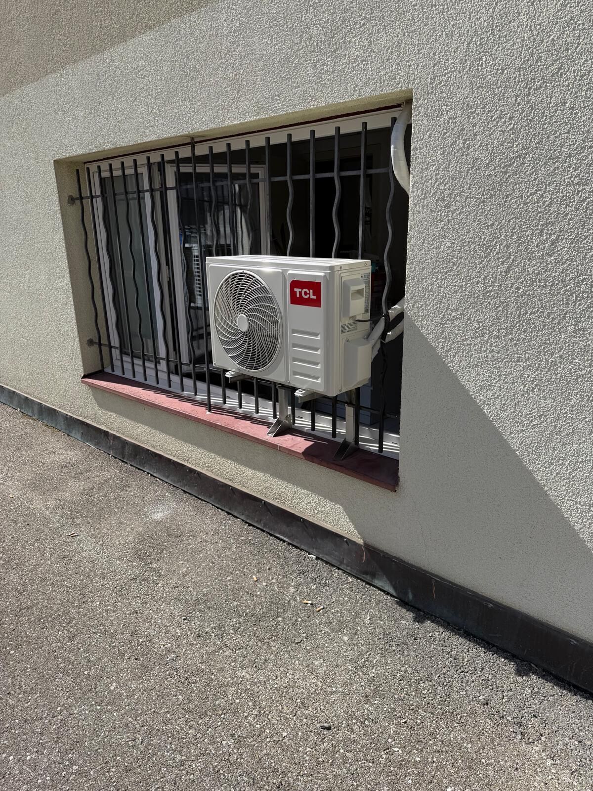 Unité extérieure de climatisation fixée devant une fenêtre